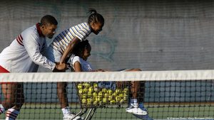 Photo extraite du film , représentant la famille Williams (le père et ses deux filles) pendant un entraînement de tennis dans leur ville natale