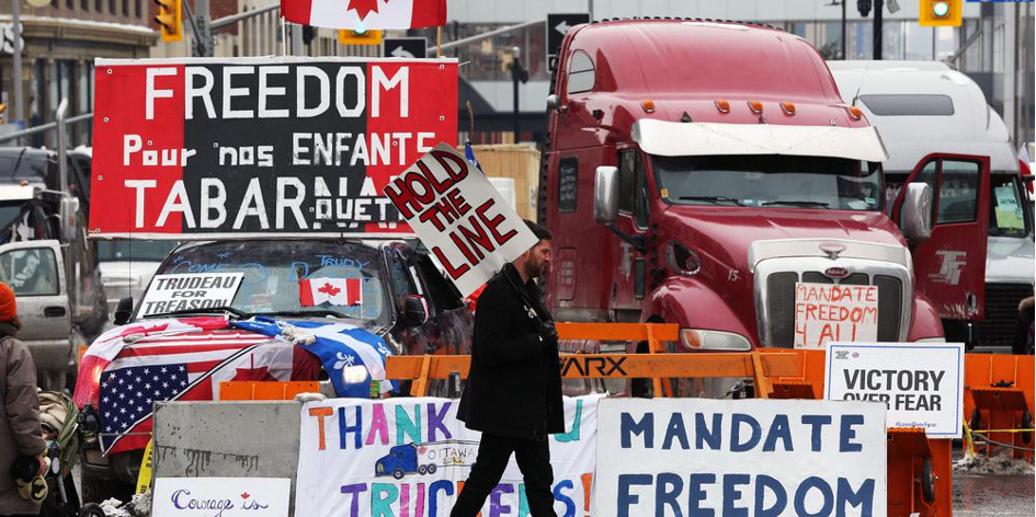 Des militants canadiens anti pass sanitaire et pass vaccinal bloquent la capitale canadienne d’Ottawa, en bloquant les routes avec des véhicules et en militant avec des banderoles (crédit photo : AFP)