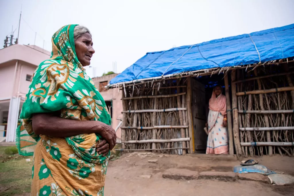 A Dalit woman standing outside her house, which has a blue tarpaulin roof, typical of Dalit houses in Narasinghpatana/ photo by Jit Chattopadhyay/TNH