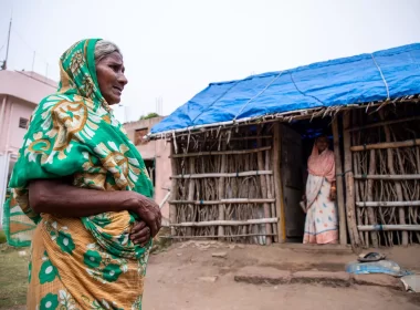 A Dalit woman standing outside her house, which has a blue tarpaulin roof, typical of Dalit houses in Narasinghpatana/ photo by Jit Chattopadhyay/TNH