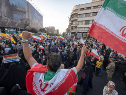 Un Iranien avec le drapeau national célèbre le cessez-le-feu après 12 jours de guerre à Téhéran, le 24 juin 2025. (Photo de Morteza Nikoubazl/NurPhoto via Getty Images)