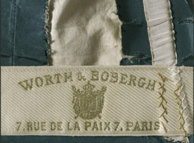 Etiquette apposée sur les créations de la maison Worth et sur laquelle figure l'adresse de la mythique institution domiciliée au 7 rue de la Paix à Paris, Robe de jour, Maison Worth & Bobergh, palaisgalliera.paris.fr